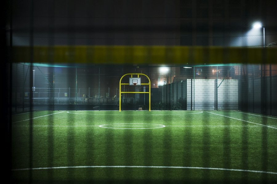 Projecteurs éclairant un petit terrain de sport le soir